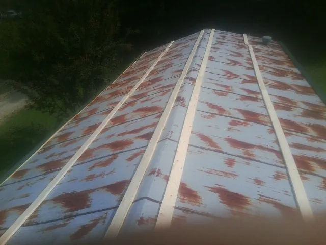 Rusted metal roof panels with new wood purlins before replacement in Hope