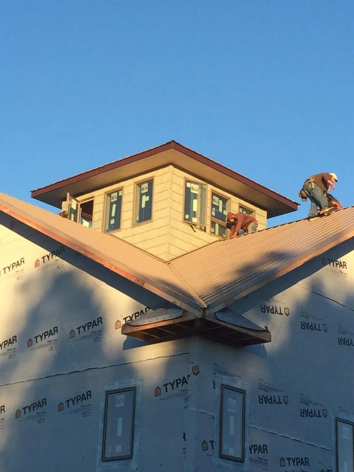 Roofers working around a rooftop cupola on a new metal roof at sunset — Roof Waterproofing in Hope by Roofing Brothers